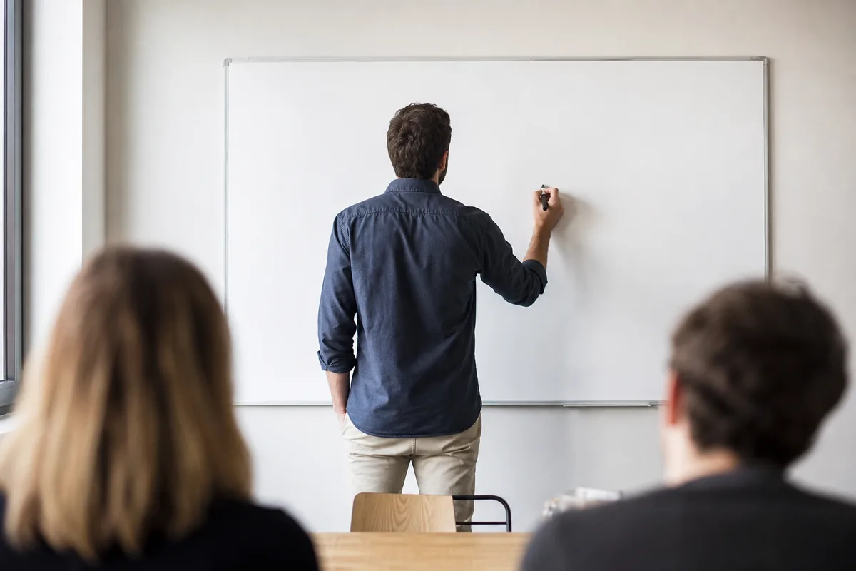 Mains d&rsquo;une personne de dos devant un tableau blanc, atelier d&rsquo;équipe en petit comité