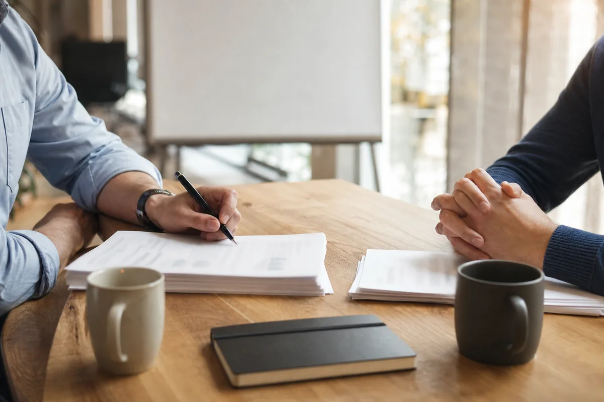 Réunion de deux dirigeants comparant des documents papier autour d&rsquo;une table en bois